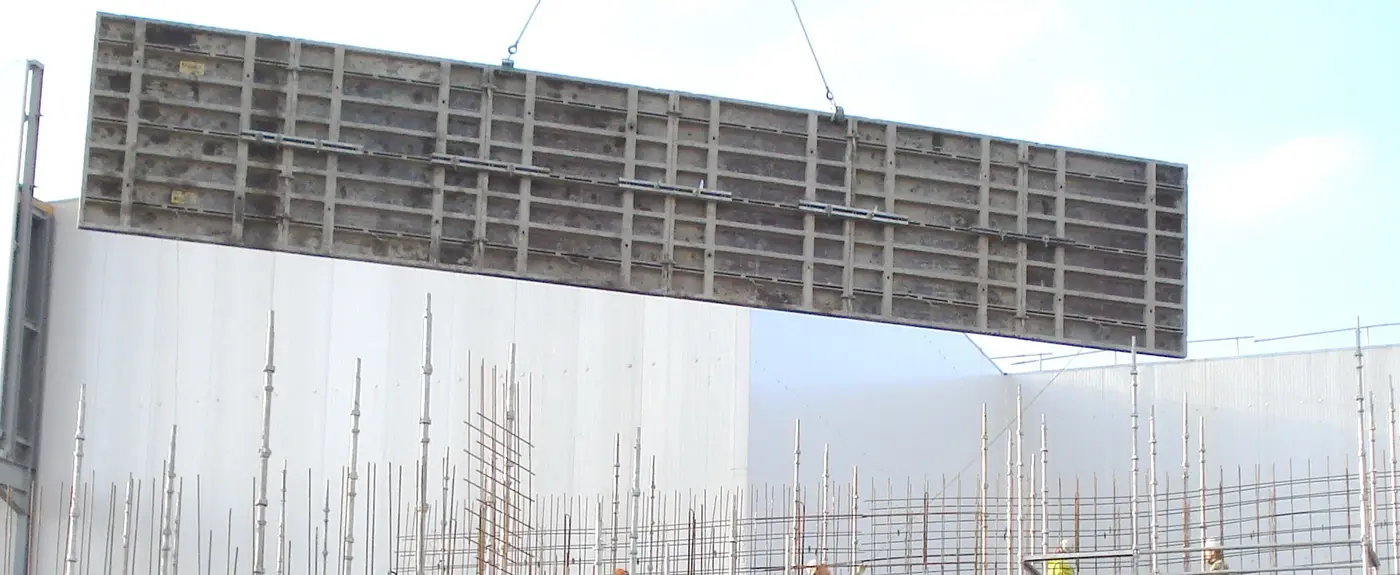 Aluminium wall formwork panel lifted into place, side rails and stiffener grid visible